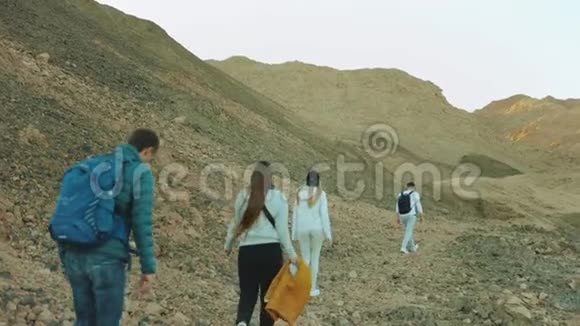 成群游客在炎热的沙漠中沿着岩石峡谷漫步游客拍照留念玩得开心沙漠山脉视频的预览图