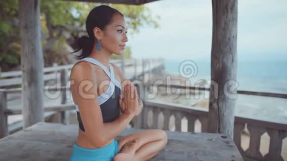 女人坐在别墅里两腿交叉坐在海边沉思视频的预览图