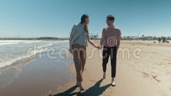 一对幸福的夫妇赤着双手走在沙滩上视频的预览图