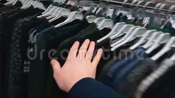 滑轮选择挂毛衣手在购物中心或商店里选择新的整洁的男性衣服检查前视频的预览图
