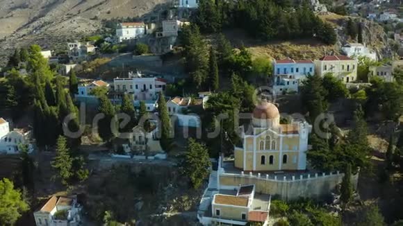 在希腊的西米岛的山腰上绕着太阳穴飞行俯瞰城市和海湾与视频的预览图