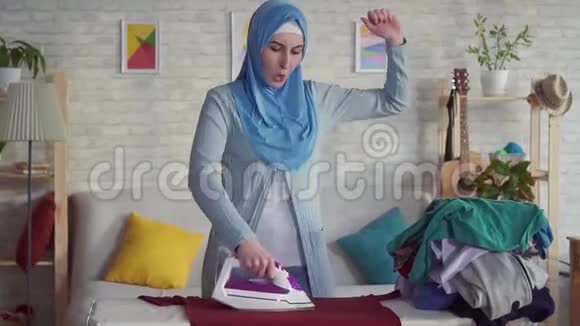 穿着头巾熨烫亚麻布的年轻穆斯林女人视频的预览图