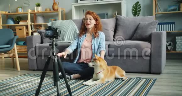 可爱的青少年博客写手与宠物狗坐在地板上录制视频博客视频的预览图