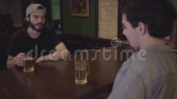 两个人坐在酒吧的桌子旁喝啤酒一起喝啤酒玩得开心在啤酒酒吧休闲视频的预览图
