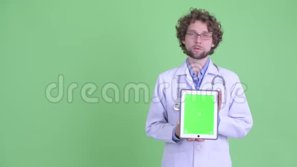 年轻的长胡子男医生在展示数码平板电脑时视频的预览图