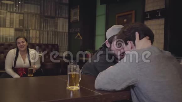 两个人坐在酒吧的一张桌子旁从事手臂摔跤丰满的女人坐在后台情感上视频的预览图