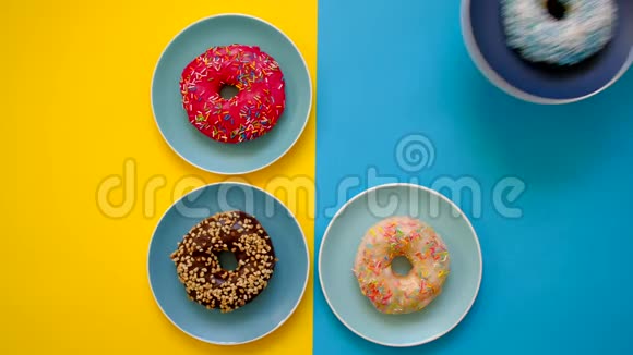 女性手放盘与甜甜圈在多色黄色和蓝色背景视频的预览图
