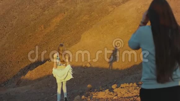 成群游客在炎热的沙漠中沿着岩石峡谷漫步游客拍照留念玩得开心沙漠山脉视频的预览图