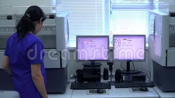 两名穿着蓝色制服的女实验室工作人员站在电脑和平板电脑前讨论研究问题视频的预览图