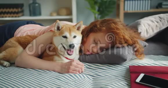 美丽的年轻女士睡在家里的沙发上拥抱可爱的小狗视频的预览图