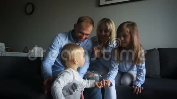 一岁的婴儿和她的父母和姐姐在家玩得很开心周末在家幸福的家庭视频的预览图