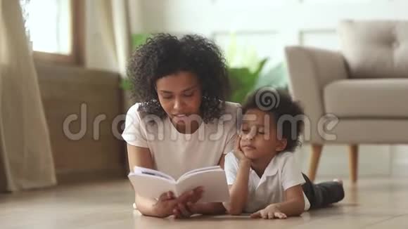 非洲儿子躺在地板上和母亲一起读童话故事视频的预览图