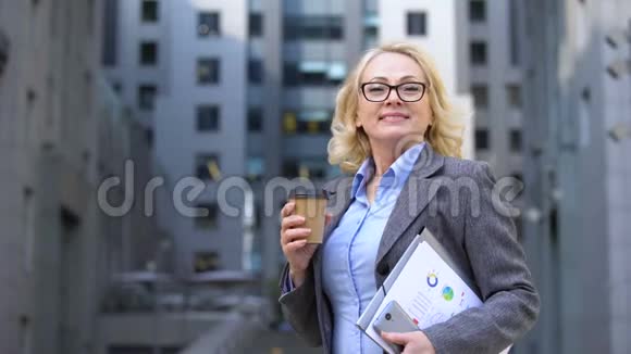 女企业工人自由呼吸手拿咖啡杯和工作文件视频的预览图