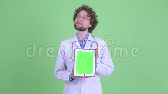 快乐的年轻胡子男医生在看数字平板电脑视频的预览图