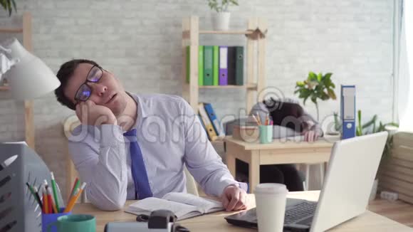 办公室里昏昏欲睡的工人一男一女在工作中睡觉接电话视频的预览图
