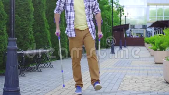 在阳光明媚的日子里一个拄着拐杖走路的时髦男人视频的预览图