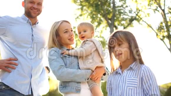 年轻的母亲抱着一个一岁的婴儿在她的怀里旁边是她的大女儿和丈夫两个幸福的家庭视频的预览图