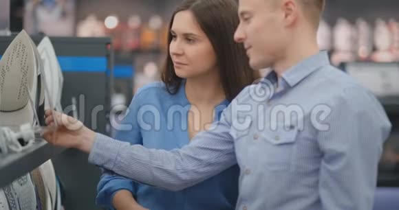 一对夫妇漂亮的男人和女人选择新的铁在消费电子商店视频的预览图