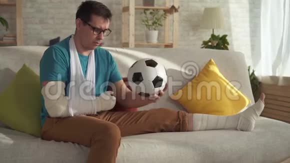 坐在沙发上拿着足球的伤心运动员画像视频的预览图