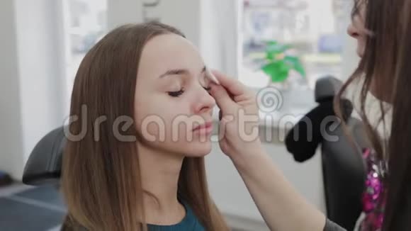专业化妆师用蘸有特殊凝胶的棉垫擦拭客户视频的预览图
