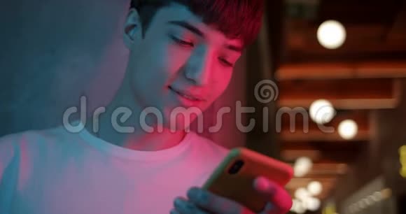 年轻时尚的Millenial男孩用他的智能手机微笑和说哇站在未来主义视频的预览图