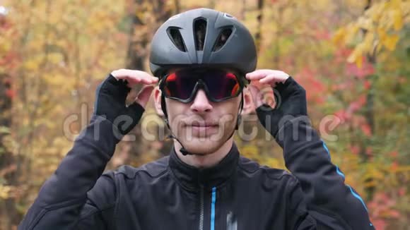 秋季公园年轻职业男性自行车运动员肖像带着黑色头盔戴眼镜的有吸引力的运动员视频的预览图