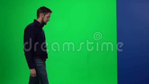 男人把手放在墙上站在绿色的屏幕背景上视频的预览图