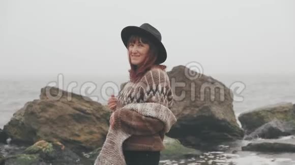 带着棕色大围巾在海边散步的年轻美女视频的预览图