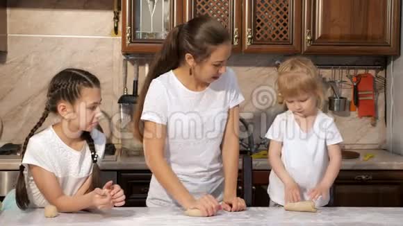 妈妈正和她的两个女儿在厨房里用面团做馅饼视频的预览图