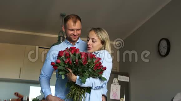 男人把一束玫瑰送给厨房里微笑的女人有爱的夫妇在厨房里放一束花视频的预览图