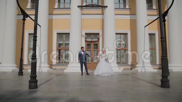 快乐的新婚夫妇在公园的柱子上跳舞视频的预览图