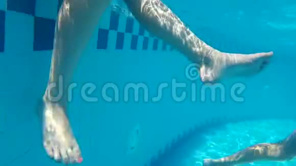 度假酒店透明泳池水中的女性腿水下景观女子移动腿蓝水游泳池视频的预览图