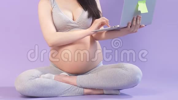 穿着瑜伽服的孕妇在笔记本电脑上上网视频的预览图