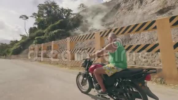 老人骑着摩托车从温泉里冒出来乘着蒸汽从山上经过乘坐摩托车旅行的成年男子视频的预览图