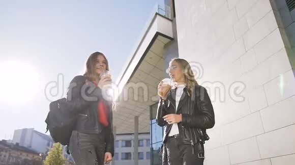 两个年轻的女孩在阳光明媚的温暖的日子里在户外散步时喝着冷的新鲜果汁最好的女朋友生活方式视频的预览图