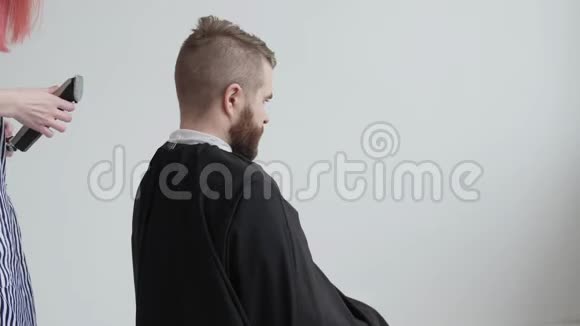 年轻的红发女理发师正在剪胡子男客户的头发视频的预览图