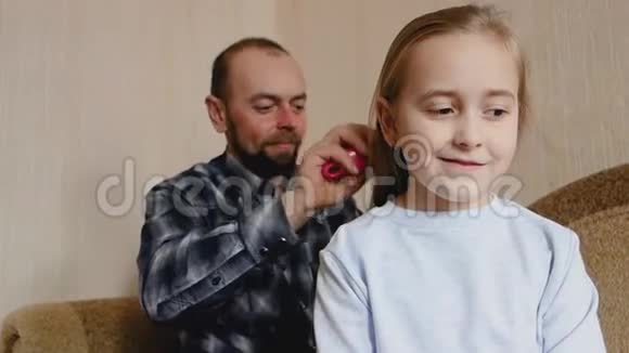 爸爸坐在沙发上梳女儿头发爸爸和女儿花时间在一起视频的预览图