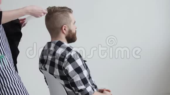 年轻的红发女理发师正在剪胡子男客户的头发视频的预览图