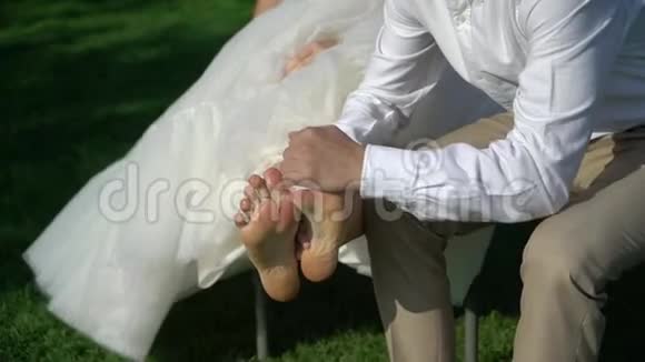 新郎新娘在公园男洗衣女在婚礼当天光着脚走路后从草地上踩脚视频的预览图