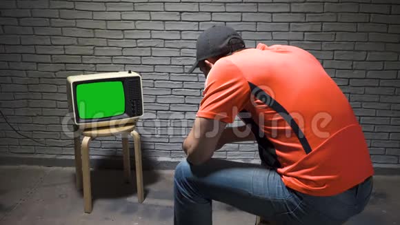 戴帽子的男人看复古电视视频视频的预览图
