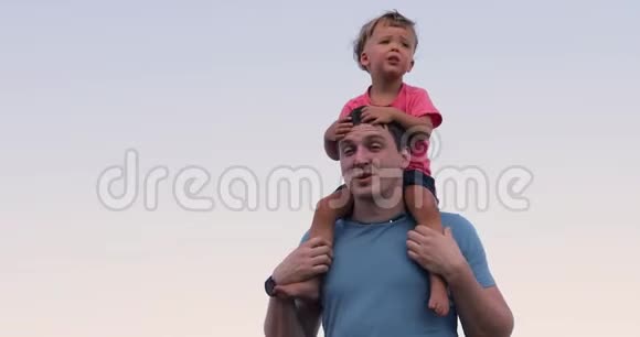 孩子坐在父亲的脖子靠在天空上视频的预览图
