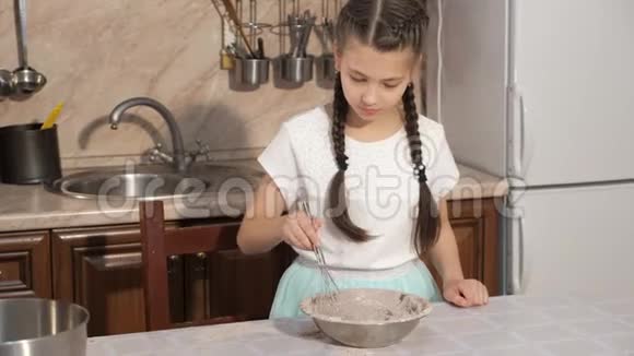 十几岁的女孩正在家厨房的碗里煮面团混合配料视频的预览图