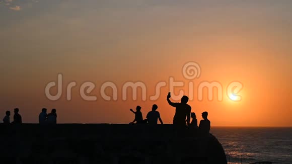 人们的剪影情侣们拍摄日落和大海的自拍照片视频的预览图