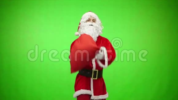 圣诞老人带着礼品袋在绿色背景下看远处Chroma键4k镜头视频的预览图