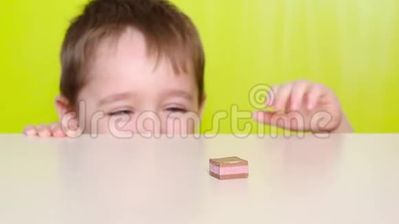 糖果在桌子上一个小可爱的婴儿从桌子上出来手拿糖果幼儿情绪视频的预览图