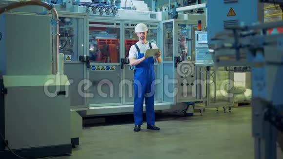 一名工人正站在一家工厂的中间手里拿着一块平板电脑视频的预览图