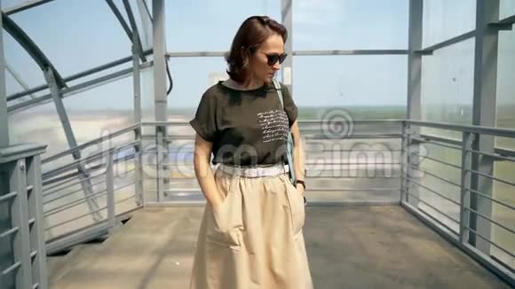 一个戴太阳镜的女人站在地上的人行桥上视频的预览图