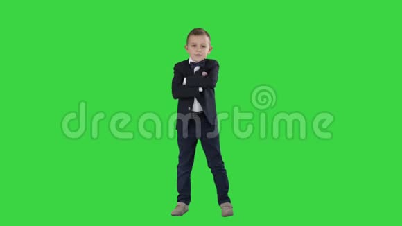 小男孩穿着正式服装在绿色屏幕上交叉双手彩色钥匙视频的预览图