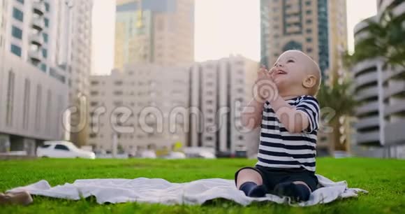 快乐的小孩子坐在草地上有着白色的雏菊城市背景视频的预览图