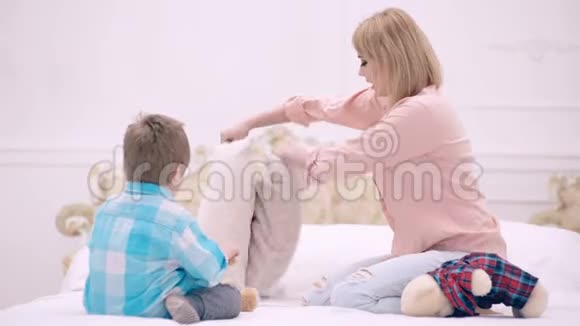 幸福的家庭在卧室里玩得很开心母亲父亲和儿子带着毛绒玩具正在床上编织孩子很开心做了房子视频的预览图